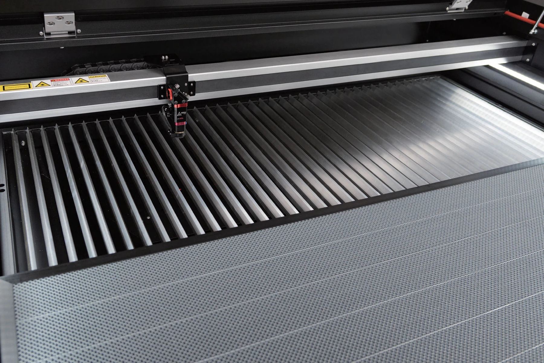 Interchangeable honeycomb and slat work tables inside an AEON NOVA machine