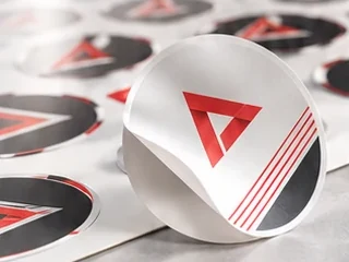 Round printed stickers kiss-cut on a self-adhesive sheet, one sticker peeled off the liner